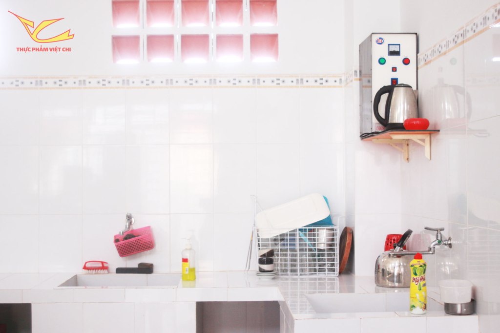 Một bếp ăn sáng và gọn gàng với bồn rửa, khu vực để đồ dùng nấu ăn, và bình đun nước.